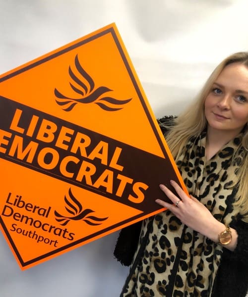 woman holding a day glo printed election campaign board